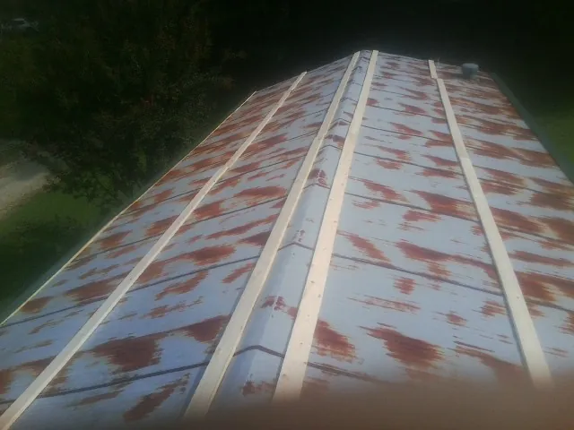 Rusted metal roof panels with new wood purlins before replacement — Storm Damage Roof Repair in West Newton by Roofing Brothers
