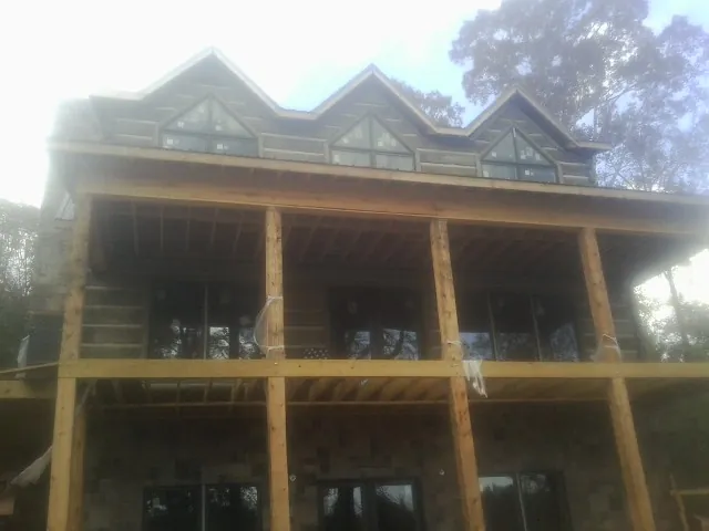 Dormers and porch framing on a large log home under construction — Roof Coating work by our crew in West Newton