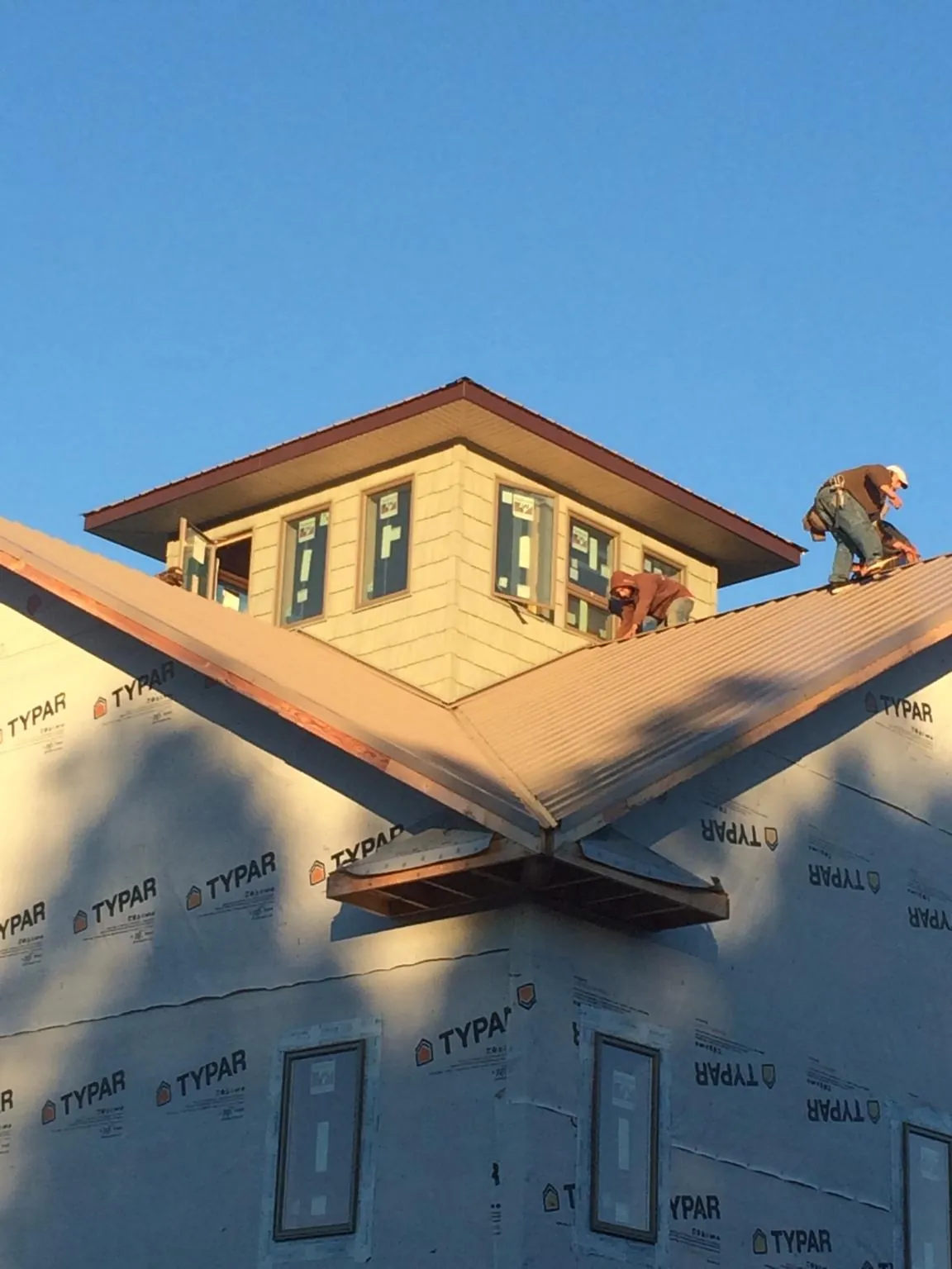 Roofers working around a rooftop cupola on a new metal roof at sunset — Roof Waterproofing in West Newton by Roofing Brothers